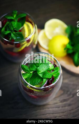 Detox bere con mirtilli rossi, menta e limone in un bicchiere su uno sfondo scuro. Bevanda sana. Foto Stock