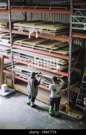 Vista ad angolo elevato di carpentieri maschi e femmine che lavorano insieme in rack nel magazzino Foto Stock