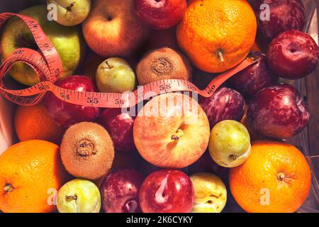 frutta estiva accatastata accanto a un metro a nastro Foto Stock