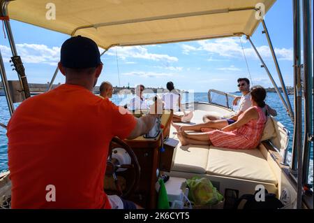 Una barca charter con turisti e equipaggio che parte dal porto di Santa Maria di Leuca per le grotte lungo la riva verso il mare Adriatico. Puglia, Italia. Foto Stock