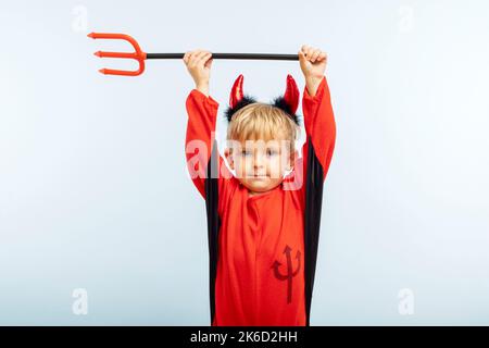 Carino ragazzo in costume diavolo Halloween con corna e tridente Foto Stock