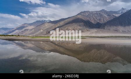 Vista panoramica del Corridoio di Wakhan in Tagikistan montagne Pamir guardando verso la gamma di kush indù in Afghanistan con riflessione nel fiume Panj Foto Stock