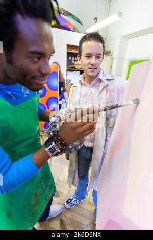 Educazione degli adulti: Dettaglio artistico. Uno studente maturo di arte che viene osservato dal suo insegnante al cavalletto. Da una serie di immagini correlate sul soggetto. Foto Stock