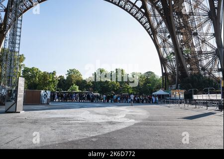 Parigi, Francia - 27 2022 agosto: Persone in coda per salire sulla Torre Eiffel. Edificio con struttura in ferro, simbolo distintivo e famosa attrazione turistica di Parigi, Francia, focus selettivo Foto Stock