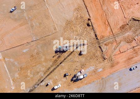 Pali di fondazione lavori pompa montata su camion in cantiere terreno di perforazione sotto colonne ad alta pressione di pompaggio calcestruzzo sudato terra Foto Stock