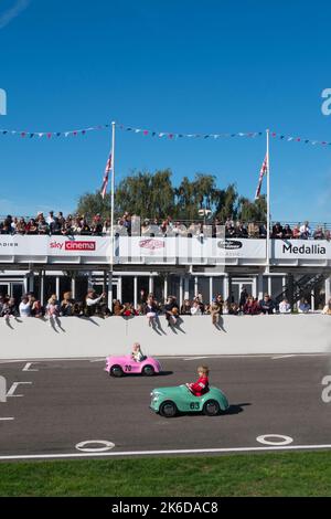 I bambini corrono con le loro auto a pedali Austin J40 sul rettilineo nella gara di Settrington Cup, Revival Meeting, circuito automobilistico di Goodwood, Goodwood, Regno Unito Foto Stock