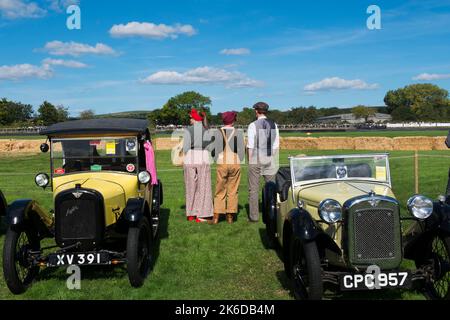 Tre persone in piedi sulla Lavant dritto in periodo Land Girl e Gent inglese abbigliamento, accanto a due Austin 7 auto, parte di un espositore per celebrare il Th Foto Stock