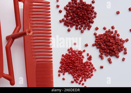 pettine in plastica rossa stampato fresco con variazioni di resine plastiche rosse Foto Stock