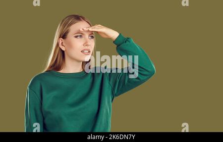 Donna che in previsione di qualcosa tiene la mano sopra gli occhi e guarda in lontananza. Foto Stock