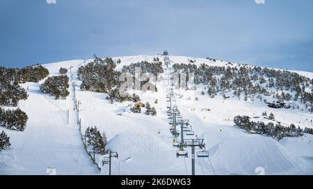 People, adults and kids, skiers and snowboarders going up on chairlift. Ski winter holidays in Andorra, El Tarter, Pyrenees Mountains, Grandvalira Foto Stock