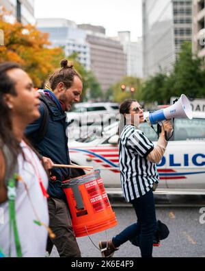 Washington, Stati Uniti. 13th Ott 2022. Un uomo ha visto battersi mentre marciando verso l'edificio del FMI. I dimostranti si sono riuniti a Edward R. Murrow Park e hanno fatto rumore con tamburi, corna, fischi e altri oggetti mentre alzano la voce sui governi del mondo che fanno soldi per i combustibili fossili senza cercare di finanziare una transizione verso l'energia pulita. Più tardi marciarono verso l’edificio dove si teneva la Conferenza stampa del FMI del G20, accumulandosi sul marciapiede. Credit: SOPA Images Limited/Alamy Live News Foto Stock