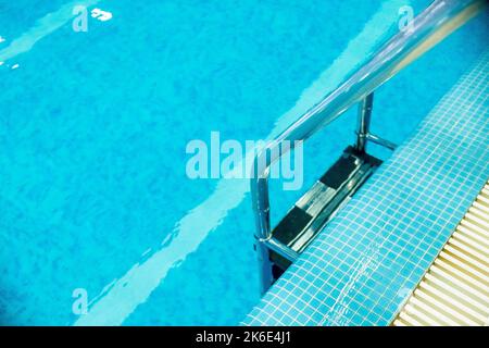 Scala per piscina con scale in piscina vuota per l'allenamento sportivo in centro ricreativo. Scala maniglioni in acciaio inox per la discesa in piscina Foto Stock