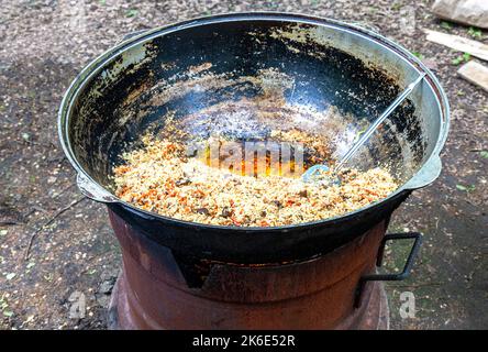 Cucina tradizionale Uzbek pilaf in un gran calderone all'aperto Foto Stock