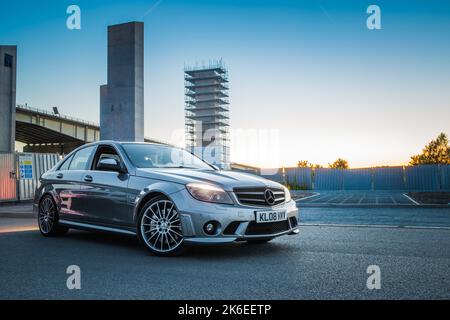 Il profilo laterale di Una Mercedes Benz C63 AMG berlina W204 2008 in Una serata di sole a Manchester Foto Stock