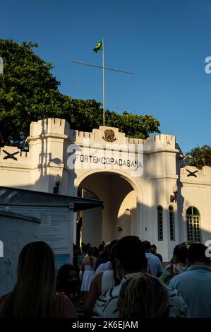 L'ingresso in stile castello del Forte Copacabana (Forte de Copacabana) con una coda di persone a questo nel tardo pomeriggio sotto il cielo azzurro soleggiato. Foto Stock