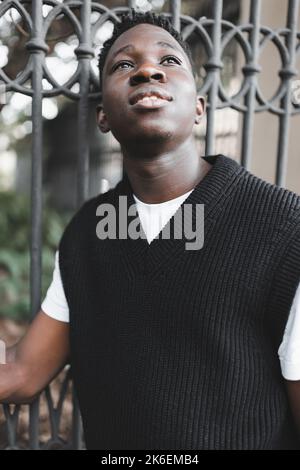 Giovane uomo afroamericano all'aperto, ritratto di strada studente, guardando in alto. Stagione autunnale o primaverile Foto Stock