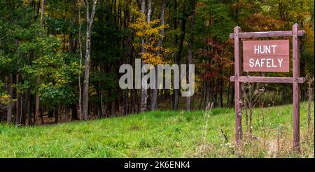 Un cartello Hunt Safely sul lato della strada nei boschi di Deerfield Township, Pennsylvania, USA in un giorno di autunno Foto Stock