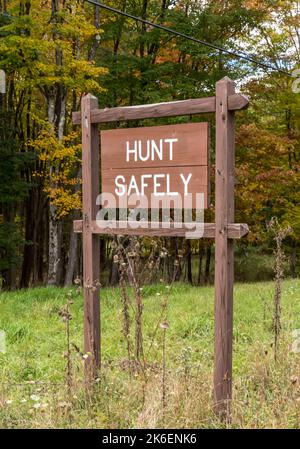 Un cartello Hunt Safely sul lato della strada nei boschi di Deerfield Township, Pennsylvania, USA in un giorno di autunno Foto Stock