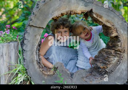 Due divertenti bambine che si divertono con una slitta in un bellissimo parco. Foto Stock