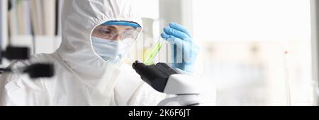 Lo scienziato in tuta protettiva studia liquidi tossici velenosi in laboratorio Foto Stock