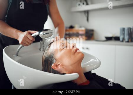 Salone di parrucchiere, shampoo e donna cliente per la cura professionale, servizio parrucchiere in startup shop, processo di bellezza, acqua di pulizia e cura dei capelli del cliente Foto Stock