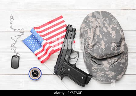 Bandiera nazionale degli Stati Uniti, berretto militare, pistola, bussola e tag su sfondo di legno bianco Foto Stock