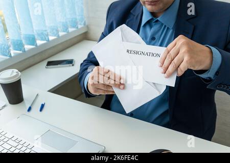 Un dipendente apre una lettera di dimissioni sul posto di lavoro. Il capo spara i dipendenti. Un uomo d'affari scrive una lettera di rassegnazione Foto Stock