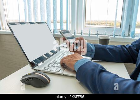 hand holding phone mockup image blank screen computer laptop for advertising text in workplace desk at office. copy space Foto Stock