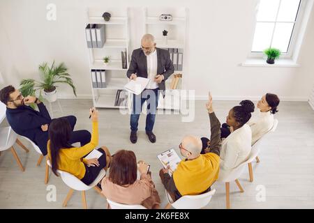 Team di dipendenti che si riuniscono, discutono qualcosa e pongono domande al proprio manager Foto Stock