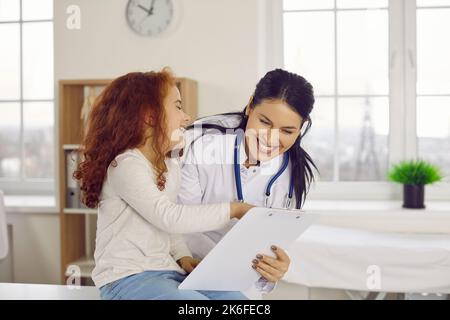 Amichevole pediatra sorridente femmina che si diverte con la bambina nel suo ufficio ospedaliero. Foto Stock