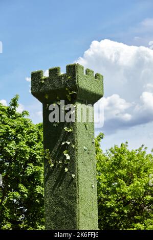 A forma di torre del castello, gli alberi verdi topiari siepano in un giardino ornamentale con fondo cielo blu. Ucraina, Kiev. Immagine sfocata, messa a fuoco selettiva Foto Stock