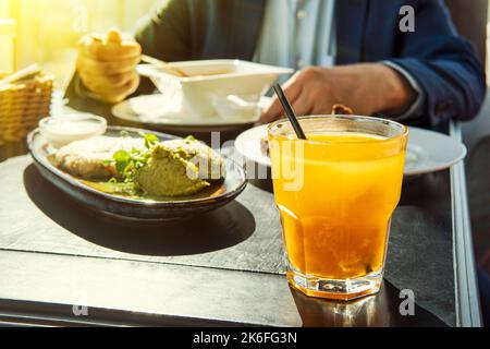 succo di spina di pesce in un bicchiere giallo su un tavolo di legno come parte di un pranzo di lavoro. Foto Stock