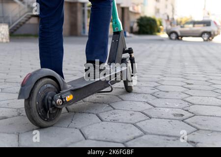 Giovane uomo d'affari in tuta in sella a uno scooter elettrico in una riunione d'affari. Concetto di trasporto ecologico. modalità di trasporto alternativa altern Foto Stock