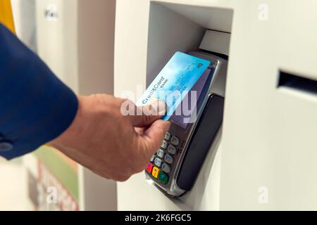 L'uomo d'affari irriconoscibile in tuta paga gli acquisti nel negozio con una carta di credito contactless. Uomo che paga con la tecnologia NFC sulla carta di credito, Foto Stock