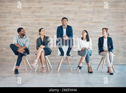 Nessuno lo meritava meglio di lui. Foto a tutta lunghezza di un bel giovane uomo d'affari seduto con i suoi colleghi mentre è il candidato scelto. Foto Stock