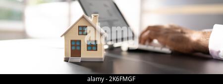 Modello Real Estate House vicino al computer portatile alla scrivania Foto Stock