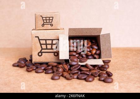 Piccole scatole di cartone con icone del carrello stampate sul lato anteriore pieno di chicchi di caffè tostati isolati su uno sfondo di carta artigianale. E-commerce Foto Stock