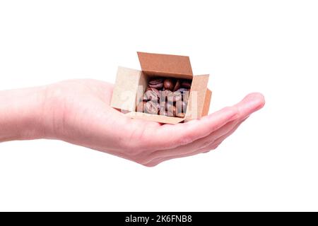 Scatola di spedizione in miniatura piena di chicchi di caffè tostati in mano isolato su sfondo bianco. Concetto di fornitore di caffè. Foto Stock