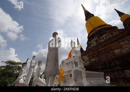 Sculture di pietra di persone che rispettano il Buddha in posa 'terra-toccante', visto qui alla base di Chedi a Wat Yai Chai Mongkhon, Ayutthaya Foto Stock