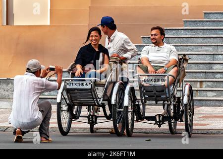 Autista di un ciclo che fotografa il turista in risciò, ho Chi Minh City Opera House Steps, Vietnam Foto Stock