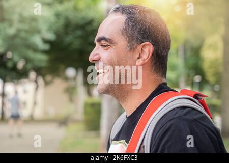 Sorridente e felice uomo con zaino in verde natura sullo sfondo. Foto Stock