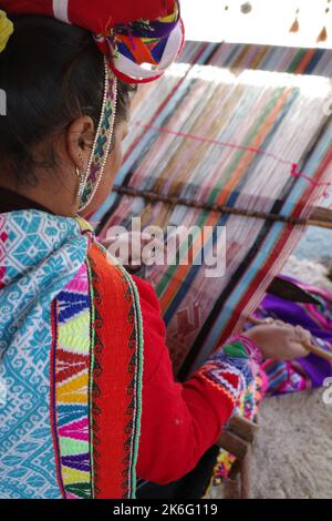 Cusco, Perù - 1 luglio, 2022: Una signora di Quechua tesse tessuti andini tradizionali utilizzando lana alpaca Foto Stock