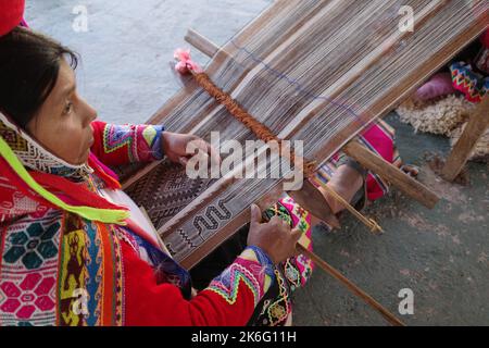 Cusco, Perù - 1 luglio, 2022: Una signora di Quechua tesse tessuti andini tradizionali utilizzando lana alpaca Foto Stock