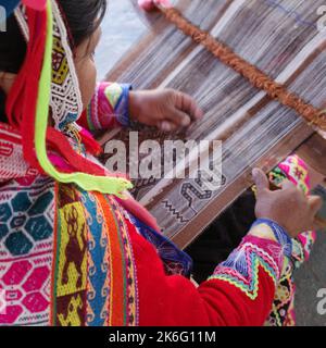 Cusco, Perù - 1 luglio, 2022: Una signora di Quechua tesse tessuti andini tradizionali utilizzando lana alpaca Foto Stock