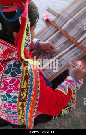 Cusco, Perù - 1 luglio, 2022: Una signora di Quechua tesse tessuti andini tradizionali utilizzando lana alpaca Foto Stock