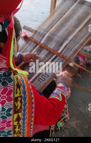 Cusco, Perù - 1 luglio, 2022: Una signora di Quechua tesse tessuti andini tradizionali utilizzando lana alpaca Foto Stock