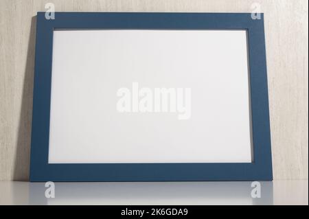 Cornice fotografica orizzontale mockup su parete bianca. cornice per diploma vuota su sfondo bianco in legno. Immagine cornice mockup. quadro diploma vuoto su bianco w Foto Stock
