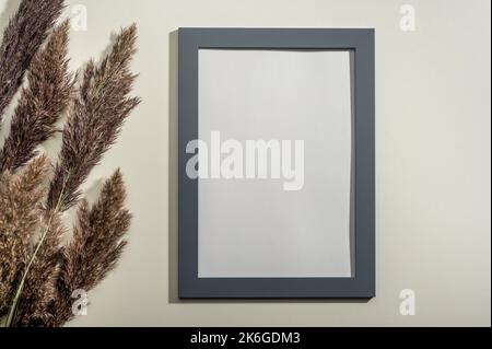 Montatura mockup e pampas d'erba naturale essiccata. Elemento decorativo interno. mockup cornice del diploma in bianco su sfondo bianco parete. Cornice con bianco vuoto Foto Stock