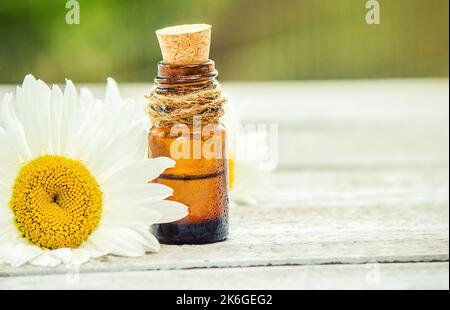 Olio essenziale camomilla in una piccola bottiglia. Fuoco selettivo. Natura. Foto Stock