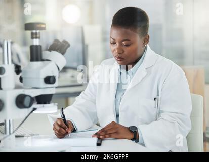 Mira a produrre dati precisi dopo un'analisi approfondita. un giovane scienziato che scrive appunti mentre lavora in un laboratorio. Foto Stock